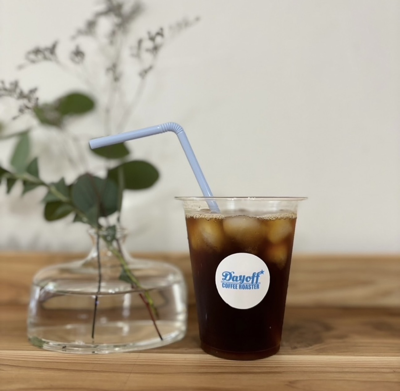 Dayoff coffee roaster のシールを貼ったカップに入ったアイスコーヒー。水色のストロー